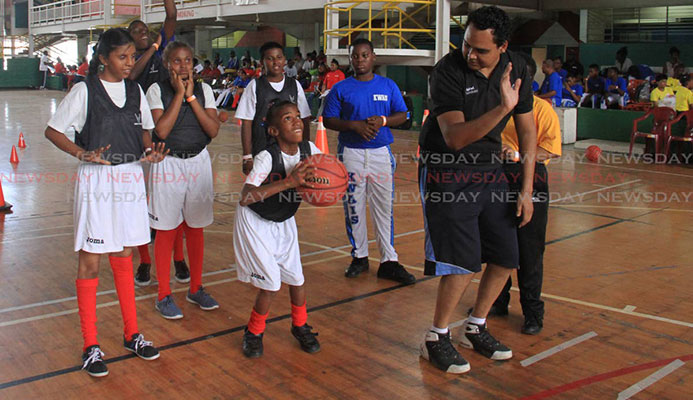 Nigel Clarke, right, shows Rayanna Flanders how to shoot during a basketball drill at the Special Olympics National Games, held at the Jean Pierre Complex, yesterday.