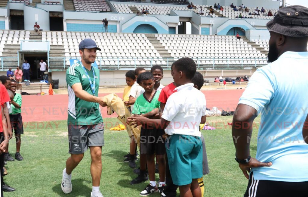 FIFA Football for Schools manager Antonio Buenano Sanchez hands out football bibs to students to separate them into teams for their age category at the start the FIFA Football for Schools Festival at Larry Gomes Stadium, Malabar, on May 7, 2024. - Faith Ayoung (Image obtained at newsday.co.tt)