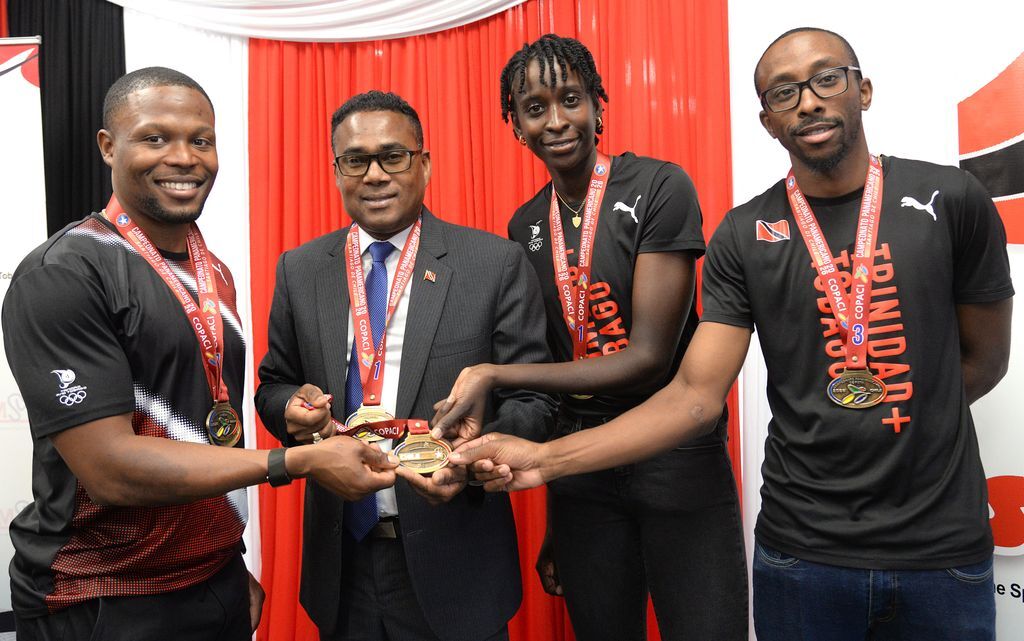 Minister of Sport and Youth Affairs, Phillip Watts, second from left, celebrates with Pan American Track Cycling Championships cyclists during a Reception at the Hasely Crawford Stadium, Port-of-Spain, yesterday. From left, Nicholas Paul, who claimed Gold medals in the keirin and match sprint, Teniel Campbell, who won gold in the women’s scratch and Akil Campbell, who claimed bronze medals in the men’s scratch, and the Men’s Elimination Race.  ANISTO ALVES (Image obtained at guardian.co.tt)